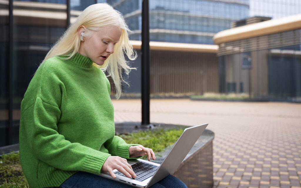 Medellång bild av en albino kvinna som arbetar med en laptop
